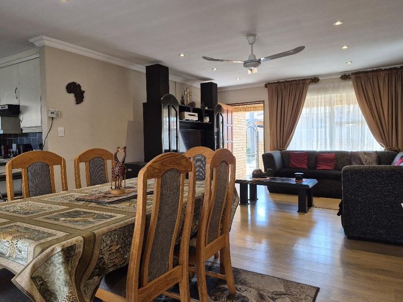 Spacious open-plan living and dining area featuring laminate flooring, recessed lighting, and a ceiling fan, with direct access to the exterior.