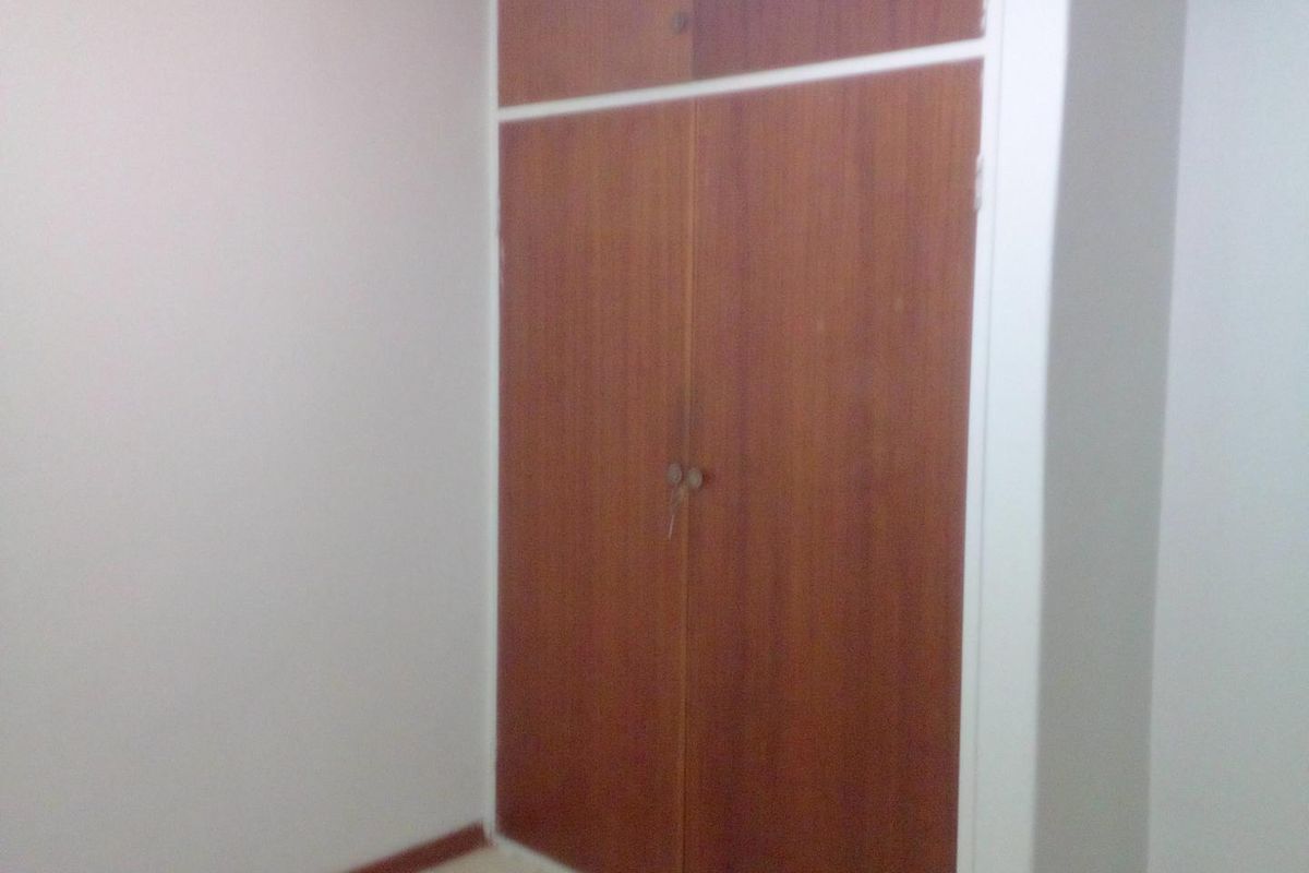 A bedroom featuring built-in wooden cupboards with overhead storage compartments.