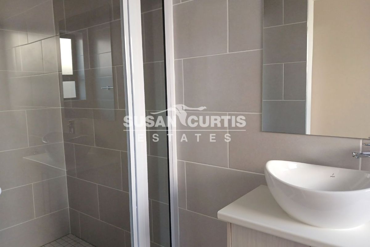 Modern bathroom featuring a glass-enclosed shower, large format grey wall tiles, and a contemporary vessel sink vanity unit.