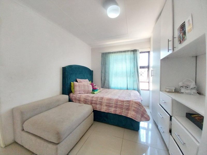 A functional bedroom featuring tiled flooring and ample built-in cupboard storage space, providing a practical layout for comfortable living.