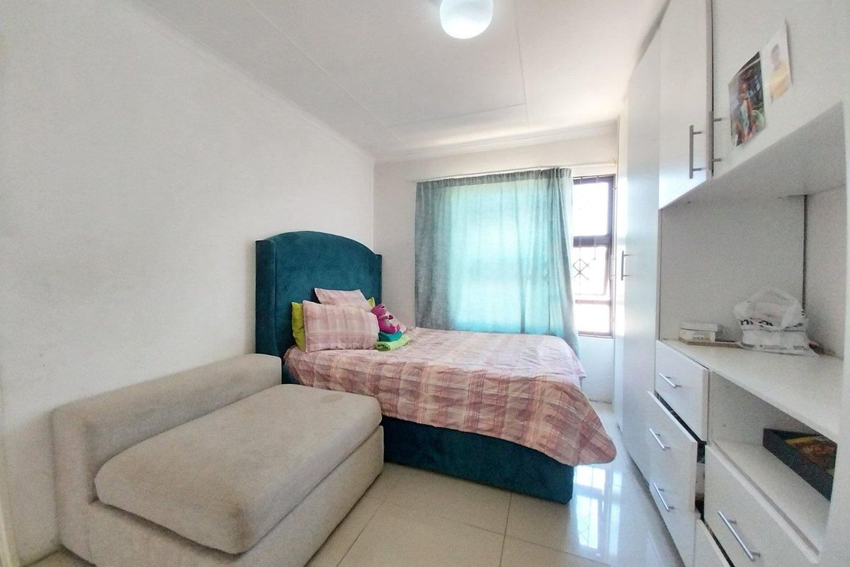 A functional bedroom featuring tiled flooring and ample built-in cupboard storage space, providing a practical layout for comfortable living.