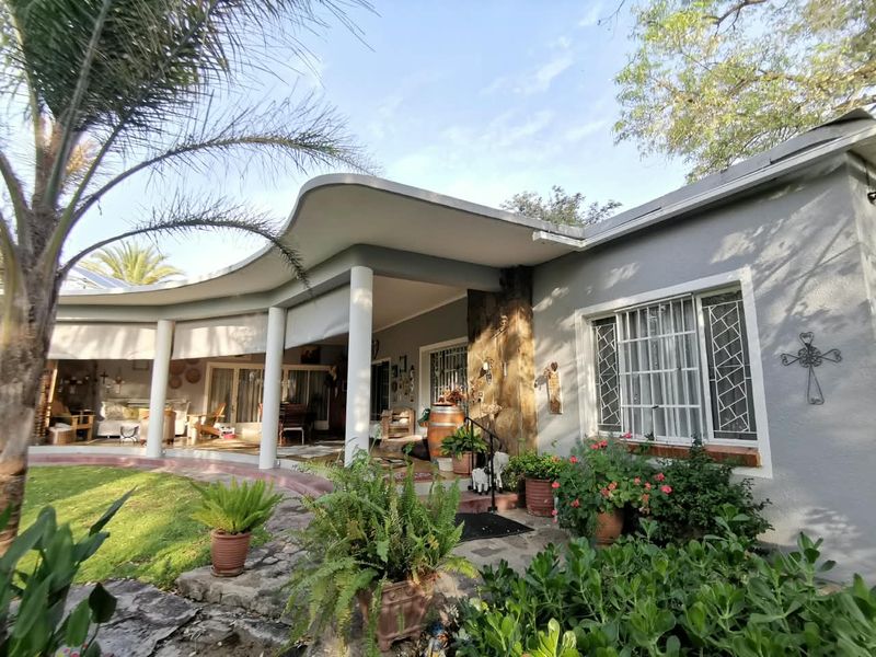 A spacious covered patio area featuring a distinctive curved roofline, stone feature wall, and direct access to the garden.