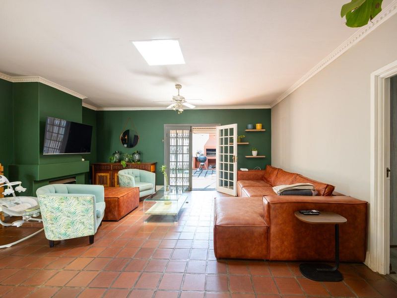 Spacious living room featuring terracotta floor tiles, a built-in fireplace, crown molding, and a skylight, with direct access to the outdoor patio area.