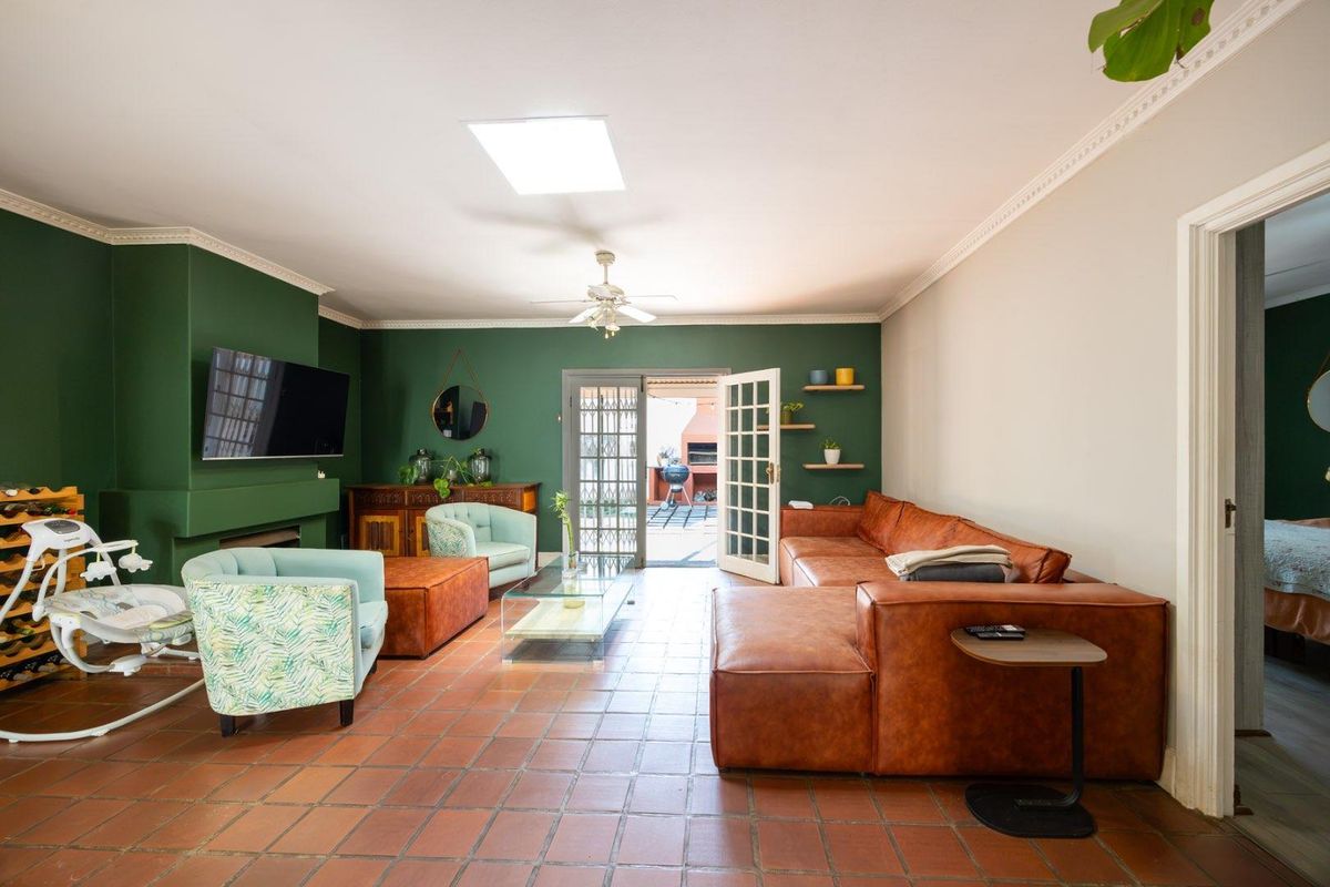 Spacious living room featuring terracotta floor tiles, a built-in fireplace, crown molding, and a skylight, with direct access to the outdoor patio area.
