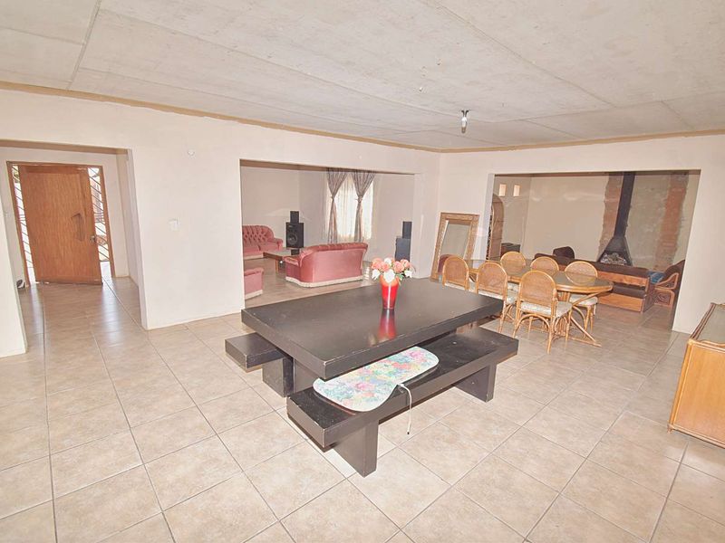 Spacious open-plan living and dining area featuring tiled floors and a built-in fireplace, offering a versatile layout with potential for modern updates.