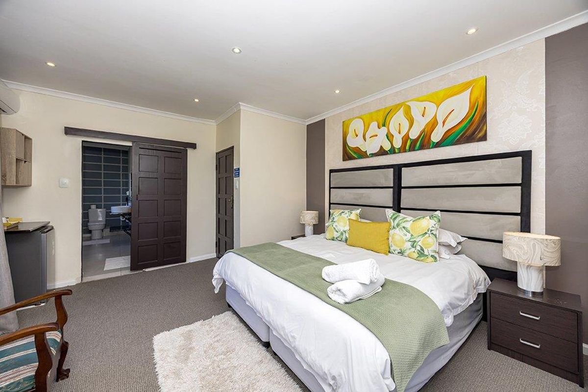 A well-maintained bedroom featuring recessed lighting, carpeted floors, and a sliding barn door leading to an en-suite bathroom.