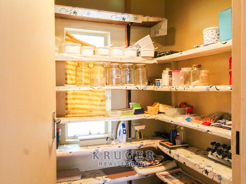 A functional walk-in pantry or scullery area featuring built-in shelving and a small window for natural light.