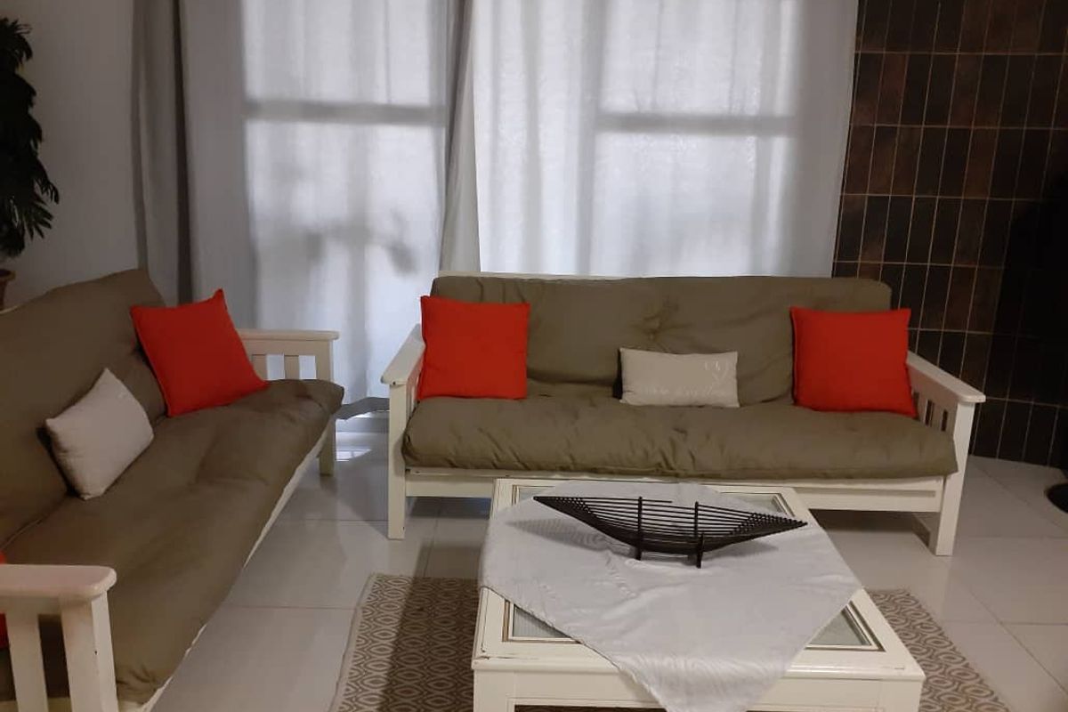 A comfortable living room area featuring tiled flooring and a dark tiled feature wall, providing a neutral base for interior updates.