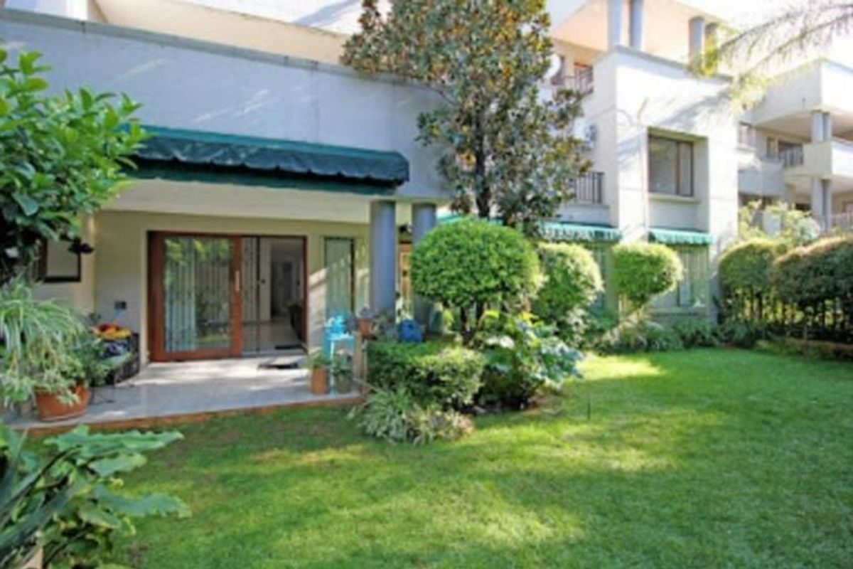 A ground-floor apartment featuring a private patio area with a retractable awning, overlooking a well-maintained garden space.