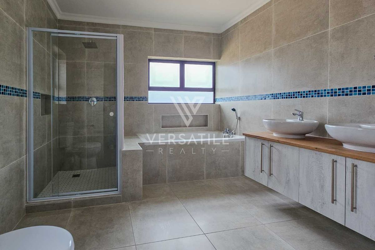 Modern bathroom featuring a glass-enclosed shower, built-in bathtub, and a floating double vanity with vessel sinks and tiled walls.