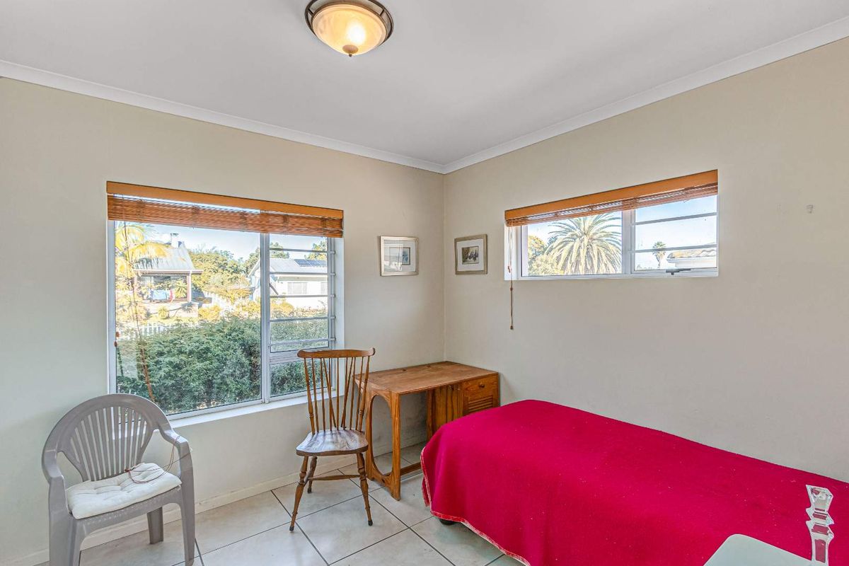 A bright bedroom featuring tiled flooring, large windows with natural light, and neutral wall finishes.