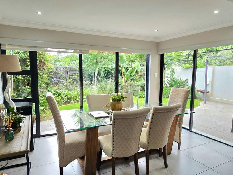 Bright dining area featuring large sliding glass doors that provide seamless access to the garden and patio, complemented by modern tiled flooring.