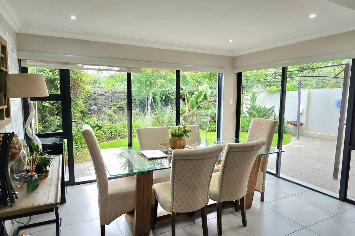 Bright dining area featuring large sliding glass doors that provide seamless access to the garden and patio, complemented by modern tiled flooring.