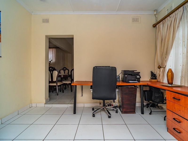 A functional home office space featuring tiled flooring and direct access to the adjacent dining area.