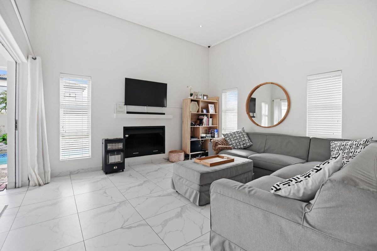 Bright living room featuring marble-look floor tiles, a built-in fireplace, and large sliding glass doors providing access to the outdoor area.