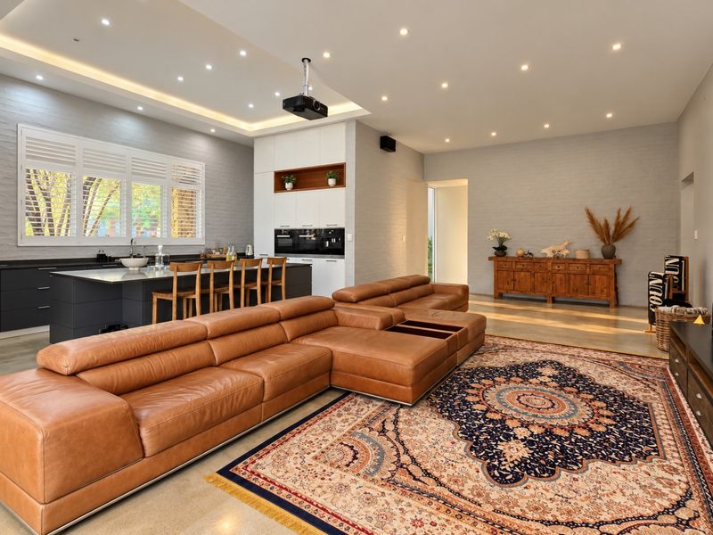 Spacious open-plan living area featuring a modern kitchen with a large island, polished concrete floors, and recessed lighting throughout.