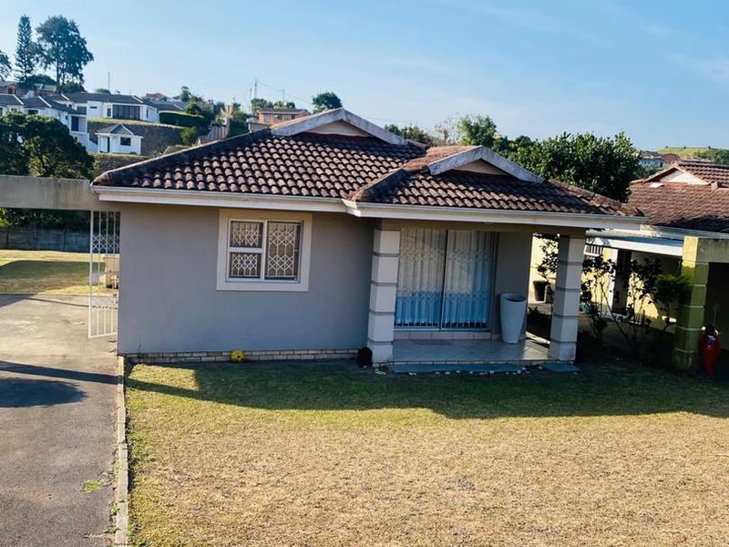 Front view of a single-story townhouse featuring a tiled roof, sliding glass entrance, and a private driveway.