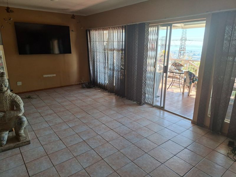 Spacious living area featuring tiled flooring and large sliding glass doors that provide access to an outdoor balcony with scenic views.