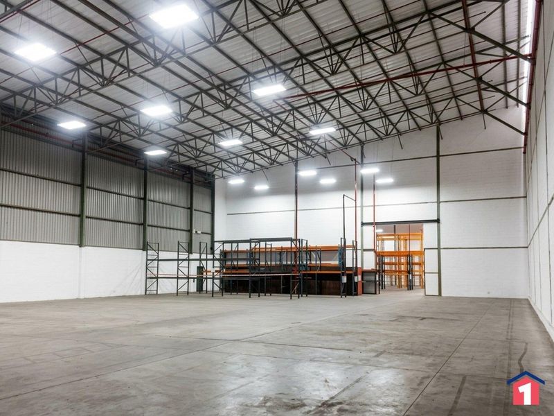 Spacious industrial warehouse featuring high ceilings with exposed steel trusses, LED lighting, fire sprinkler system, and concrete flooring.