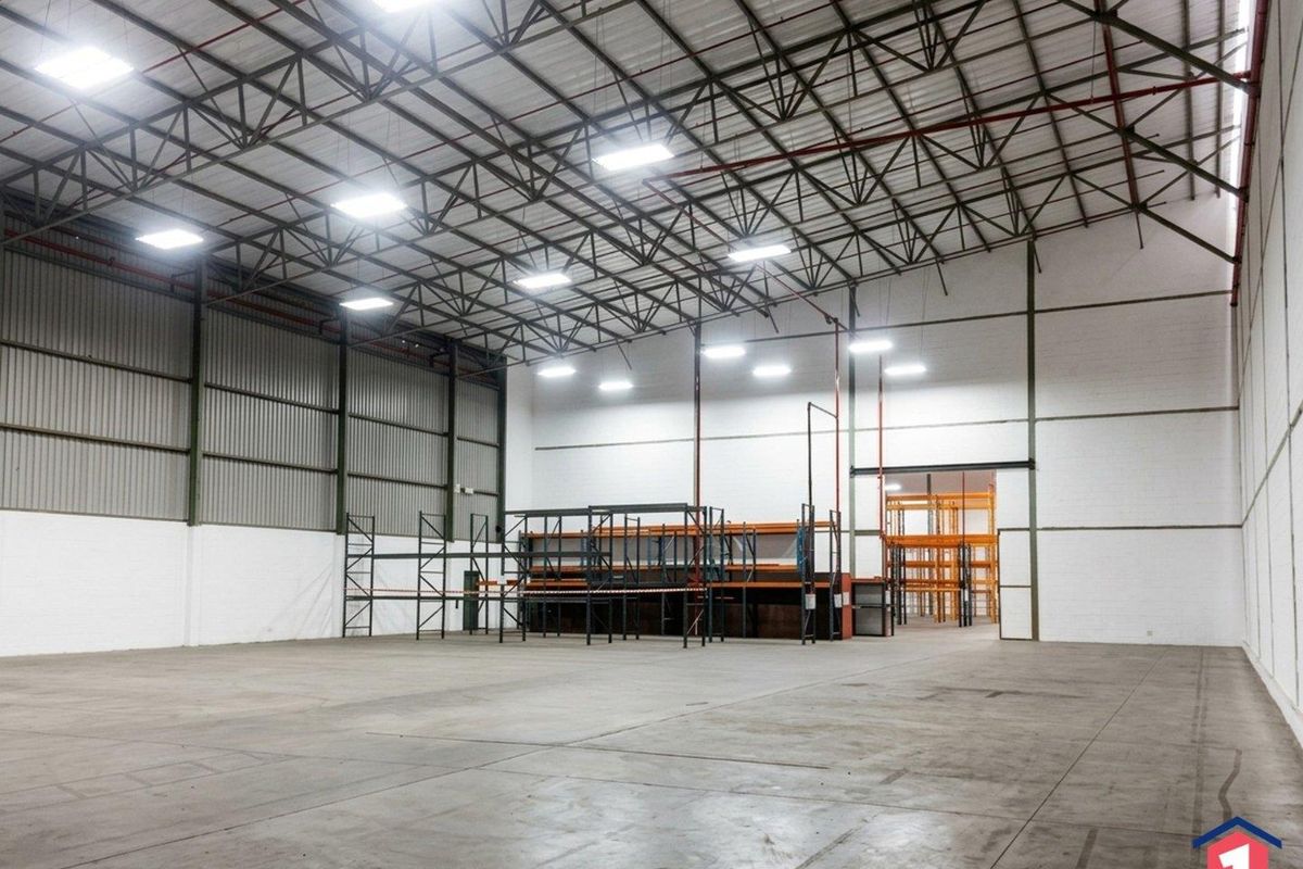 Spacious industrial warehouse featuring high ceilings with exposed steel trusses, LED lighting, fire sprinkler system, and concrete flooring.