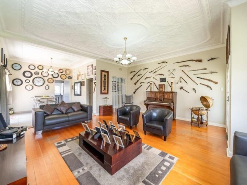 Spacious living room featuring original pressed metal ceilings, ornate ceiling roses, and polished hardwood flooring, offering a classic architectural aesthetic.