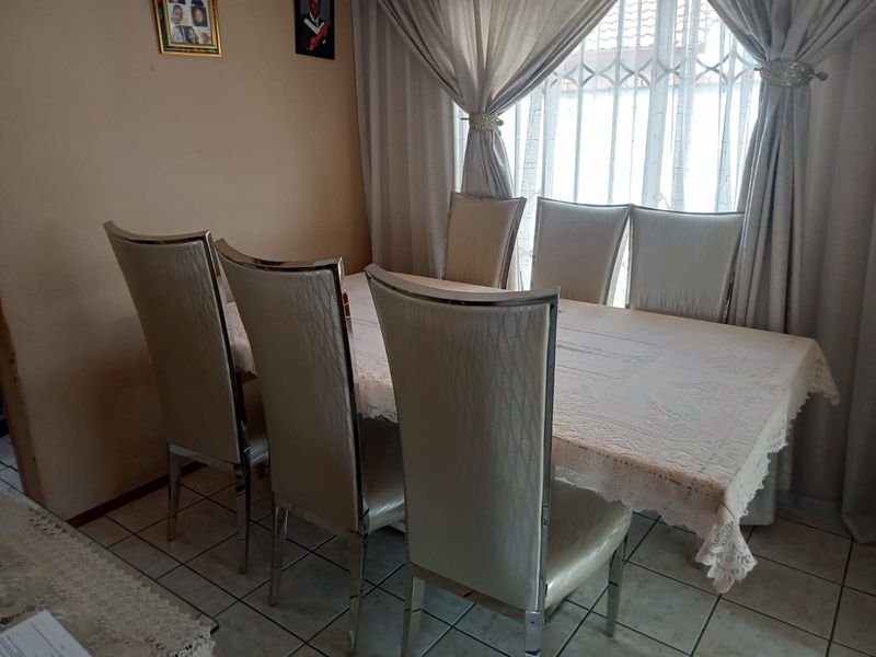 A dining room area featuring tiled flooring and a window fitted with a security gate, providing a functional space for meals.
