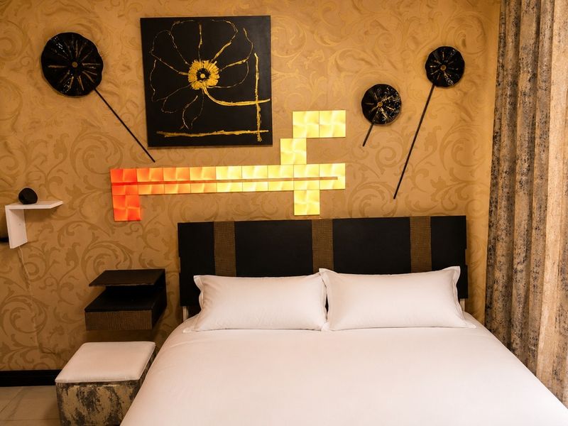 A well-maintained bedroom featuring decorative patterned wallpaper and a modern floating bedside shelf.