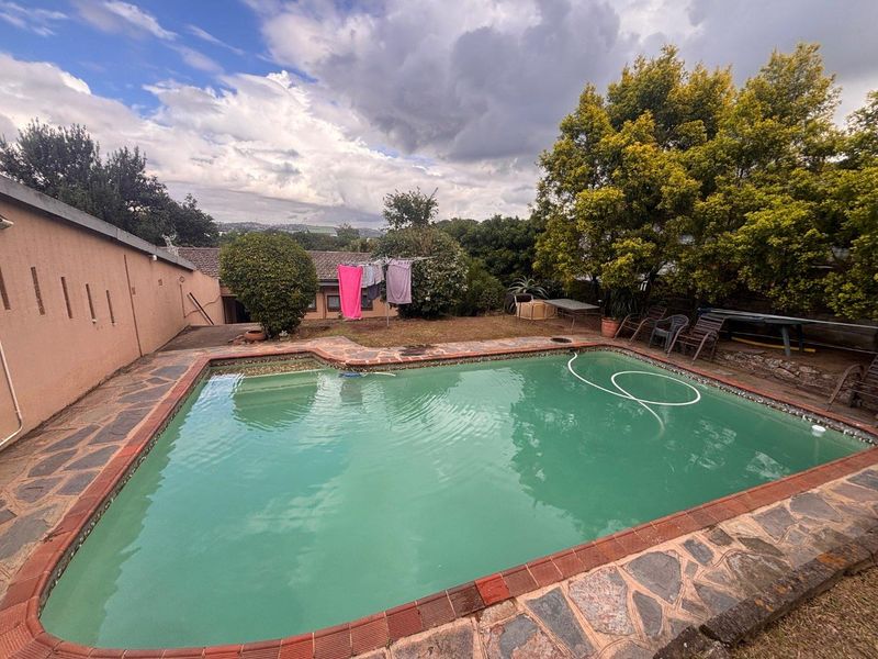 Outdoor swimming pool area featuring stone-paved surround and established garden landscaping in a rear yard setting.
