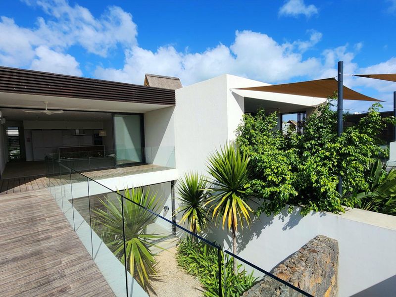 Modern townhouse exterior featuring a wooden deck, glass balustrades, and a contemporary architectural design with integrated outdoor shading.