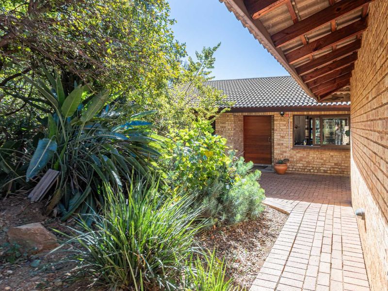 A charming front entrance featuring a face brick facade, tiled roof, and a paved walkway leading to a solid wooden front door.