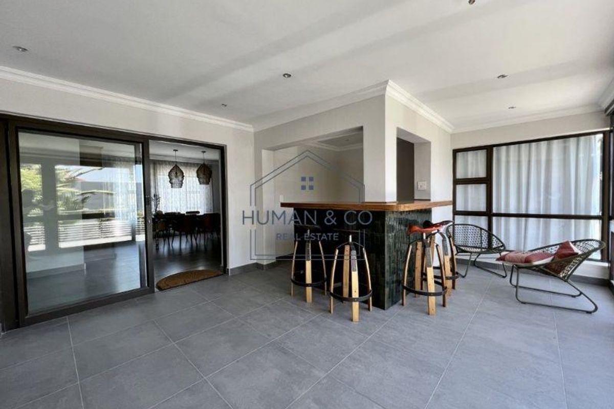 Spacious indoor entertainment area featuring a built-in bar, large format floor tiles, and sliding glass doors leading to an adjacent dining space.