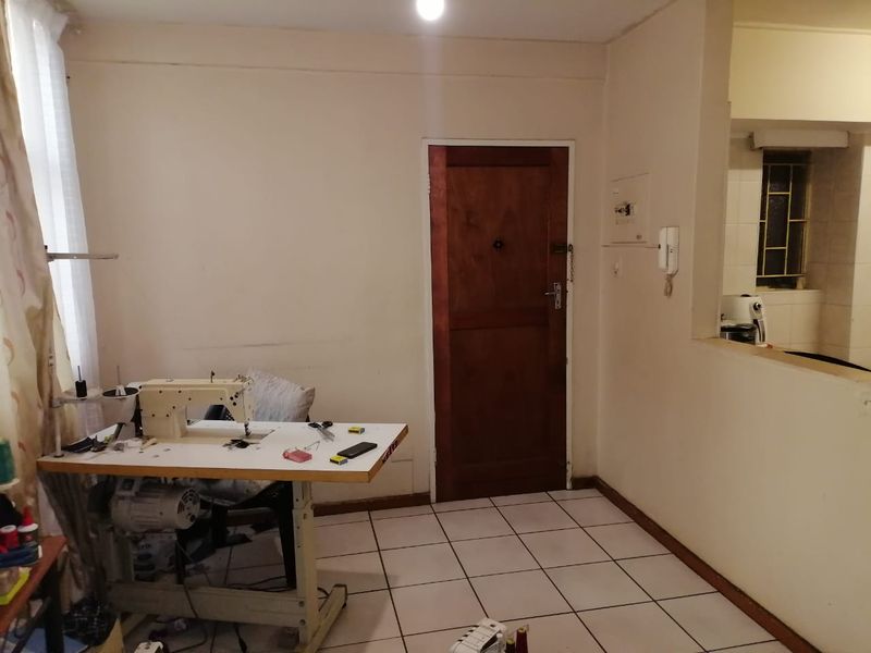 Open plan living area featuring tiled flooring, an intercom system, and a pass-through window connecting to the kitchen area.