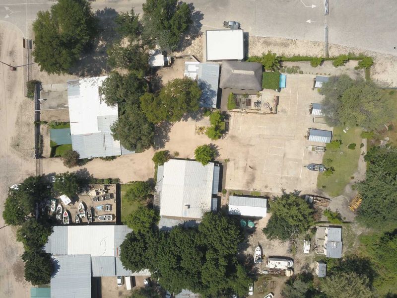 Aerial view of a mixed-use property featuring multiple detached buildings with various roof types, extensive paved parking, and mature landscaping.