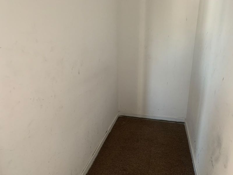A small, empty utility or storage space featuring carpet flooring and walls in need of repainting.