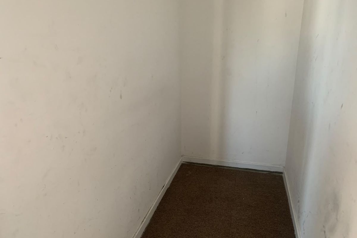 A small, empty utility or storage space featuring carpet flooring and walls in need of repainting.