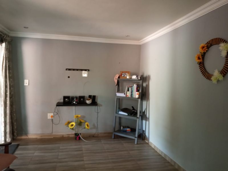 A living room area featuring neutral grey walls, crown molding, and tiled flooring, providing a clean and functional space.
