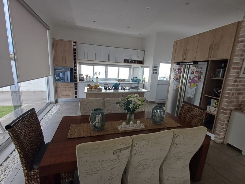 Modern open-plan kitchen and dining area featuring contemporary cabinetry, a central island with gas hob, and large windows providing ample natural light.
