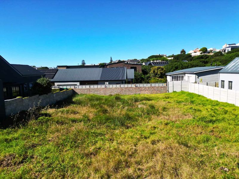 A vacant residential plot featuring established boundary walls and surrounding residential development in a quiet neighborhood setting.