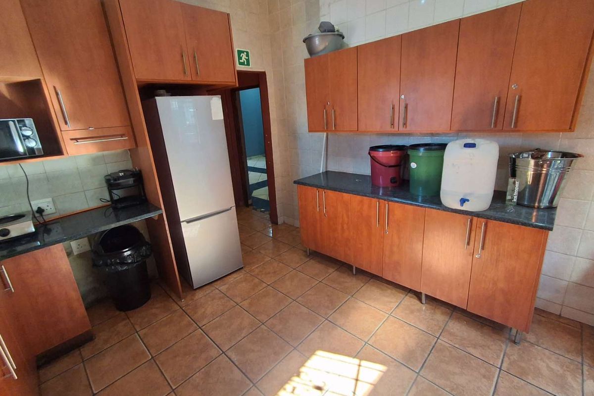 A functional kitchen featuring wood-finish cabinetry, granite countertops, and tiled flooring, providing ample storage and workspace.