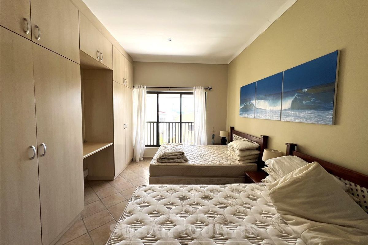 Spacious bedroom featuring extensive built-in cabinetry with integrated desk space, tiled flooring, and sliding door access to a private balcony.