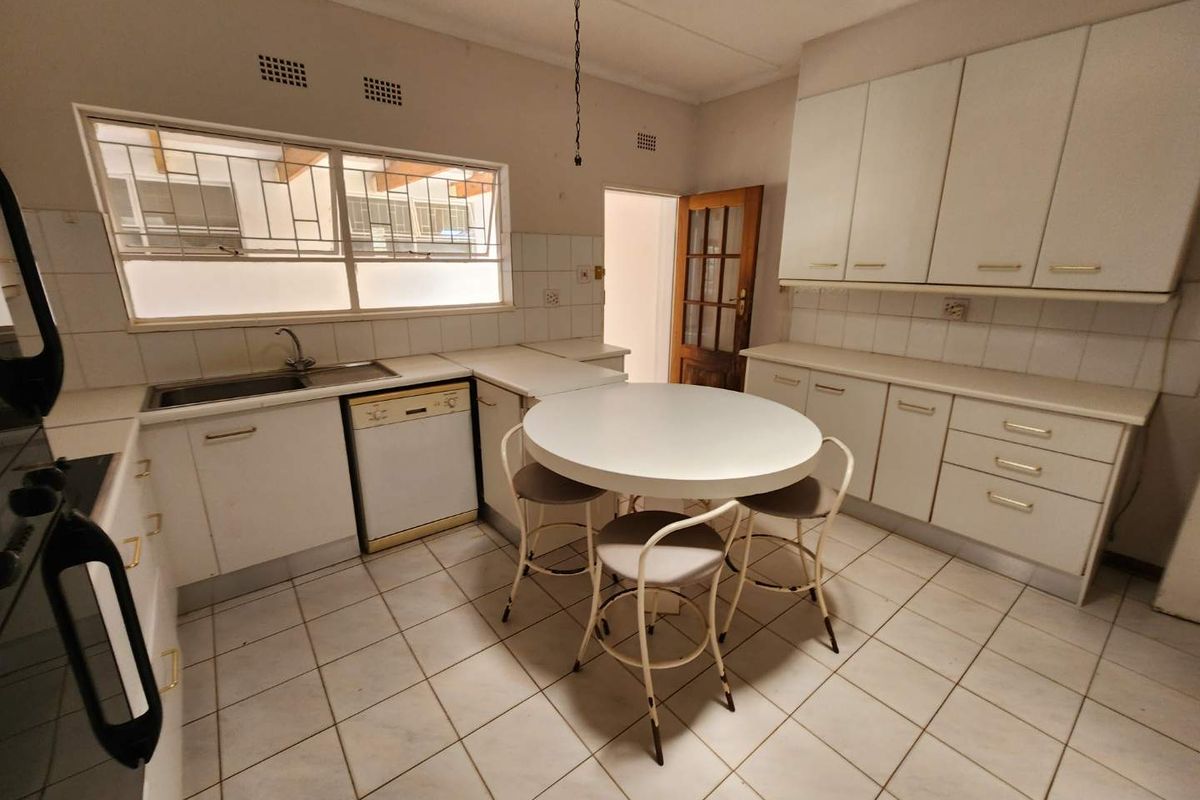 A functional kitchen featuring white cabinetry, tiled flooring, a built-in sink, and integrated dishwasher space, offering a clean and practical layout.