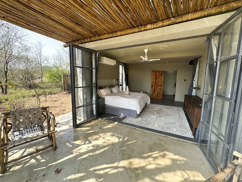 Spacious bedroom featuring bi-fold glass doors opening onto a covered patio, complete with a ceiling fan and air conditioning for comfort.