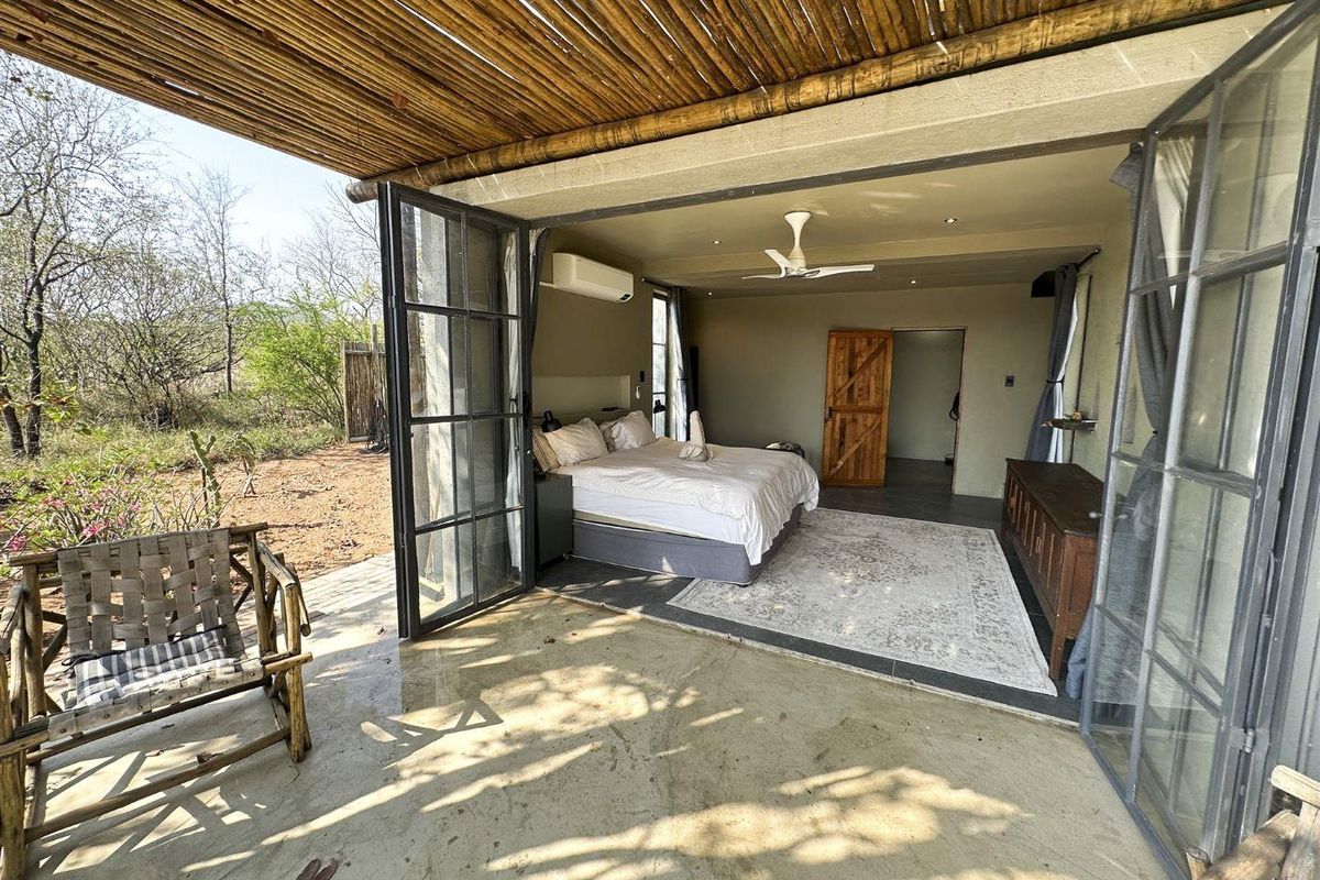 Spacious bedroom featuring bi-fold glass doors opening onto a covered patio, complete with a ceiling fan and air conditioning for comfort.