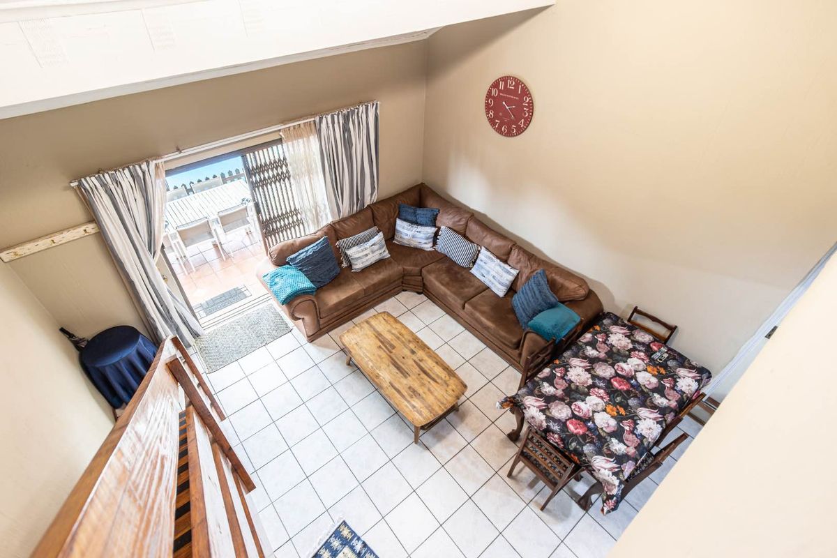 Spacious living area with vaulted ceilings, tiled flooring, and direct access to an outdoor patio through sliding glass doors.