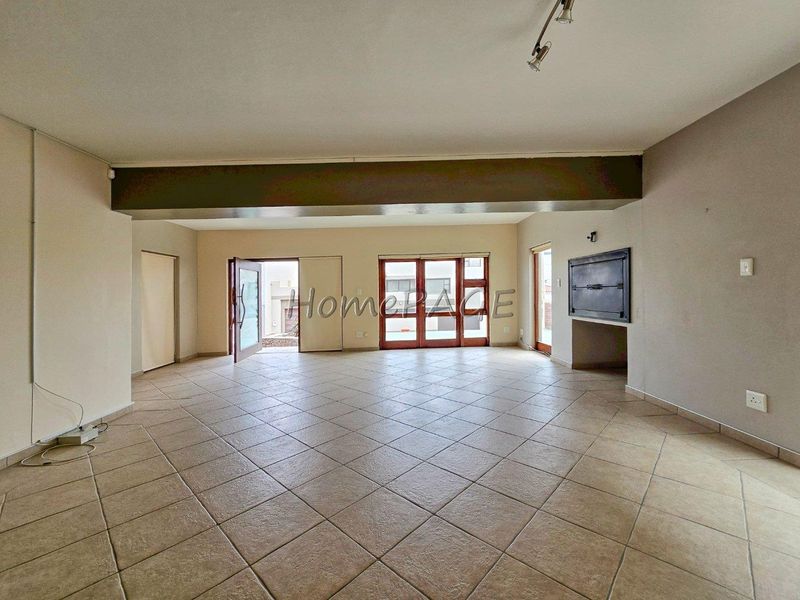 Spacious open-plan living area featuring tiled flooring, a built-in fireplace, and multiple glass doors providing access to the exterior.