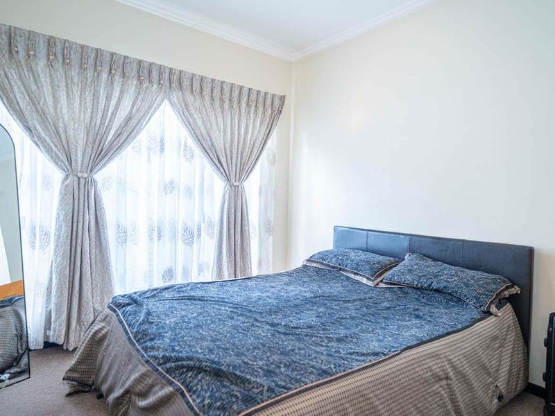 A well-lit bedroom featuring neutral walls, carpeted flooring, and decorative coving, providing a comfortable and functional living space.