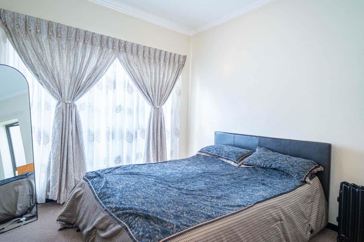 A well-lit bedroom featuring neutral walls, carpeted flooring, and decorative coving, providing a comfortable and functional living space.