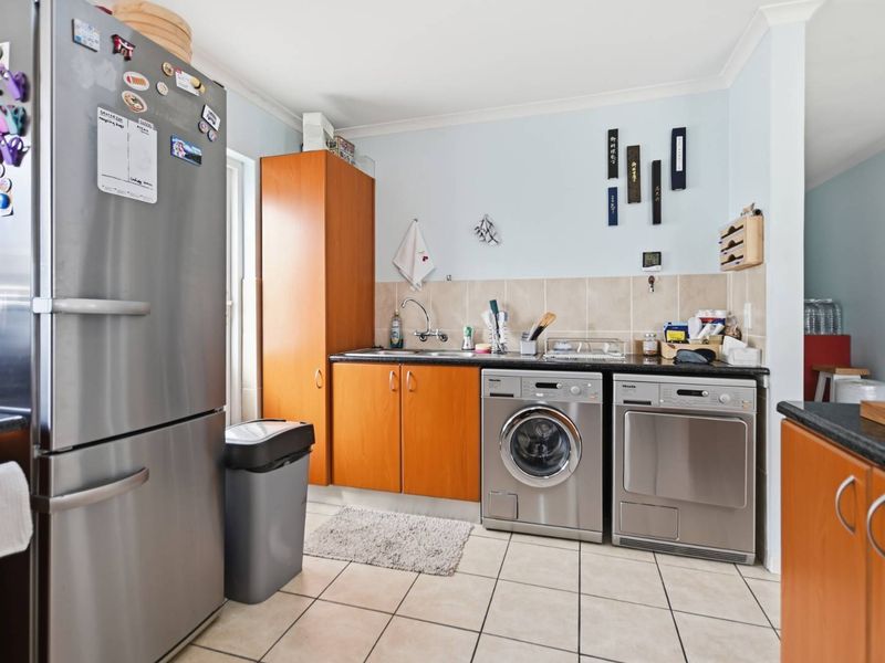 Functional laundry area featuring built-in wooden cabinetry, tiled splashback, and dedicated space for laundry appliances.