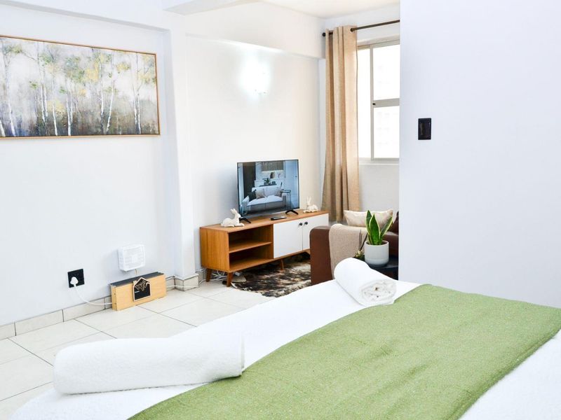 A bright bedroom featuring tiled flooring and a window, providing a clean and functional living space.
