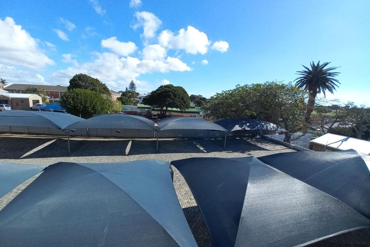 Elevated view of a paved parking area featuring multiple shade cloth structures for vehicle protection.